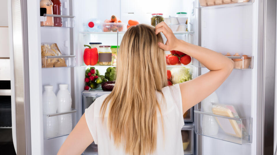 Rear,View,Of,Young,Woman,Looking,In,Fridge,At,Kitchen