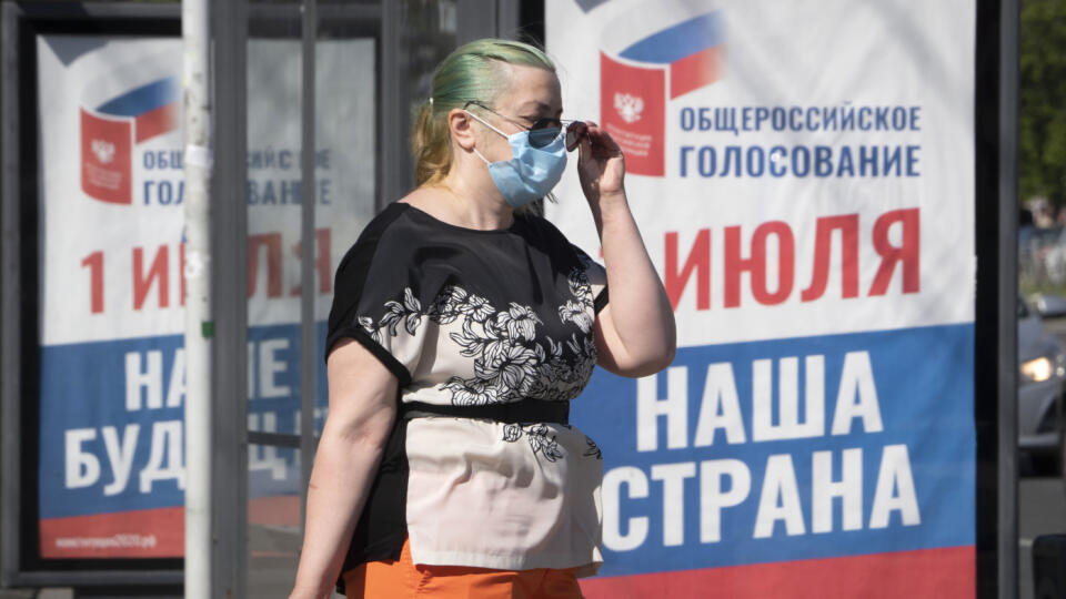 Žena s ochranným rúškom na zabránenie šíreniu nového koronavírusu prechádza okolo predvolebného bilbordu s nápisom