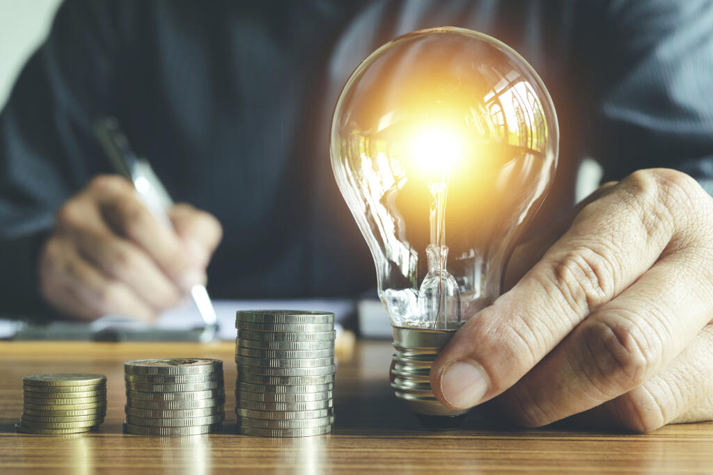 Business,Man,Holding,Light,Bulb,On,The,Desk,In,Office