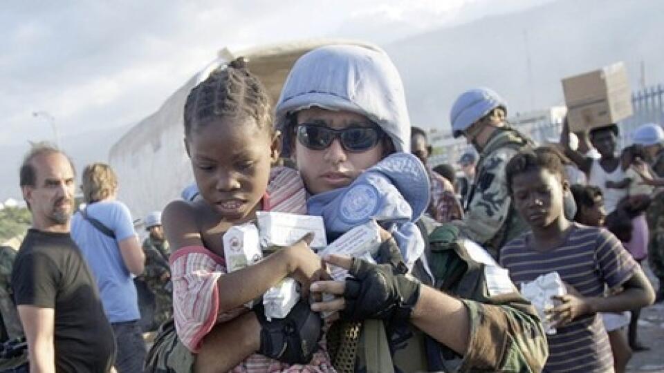 Argentínsky vojak nesie dievčatko s prídelovým balíčkom v stredisku Svetového potravinového fondu OSN pri Port-au-Prince, zriadenom pre ľudí odkázaných na pomoc po ničivom zemetrasení na Haiti.