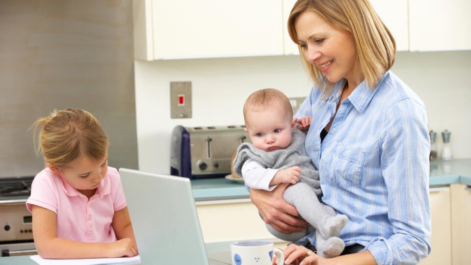 Mother,With,Children,Using,Laptop,In,Kitchen