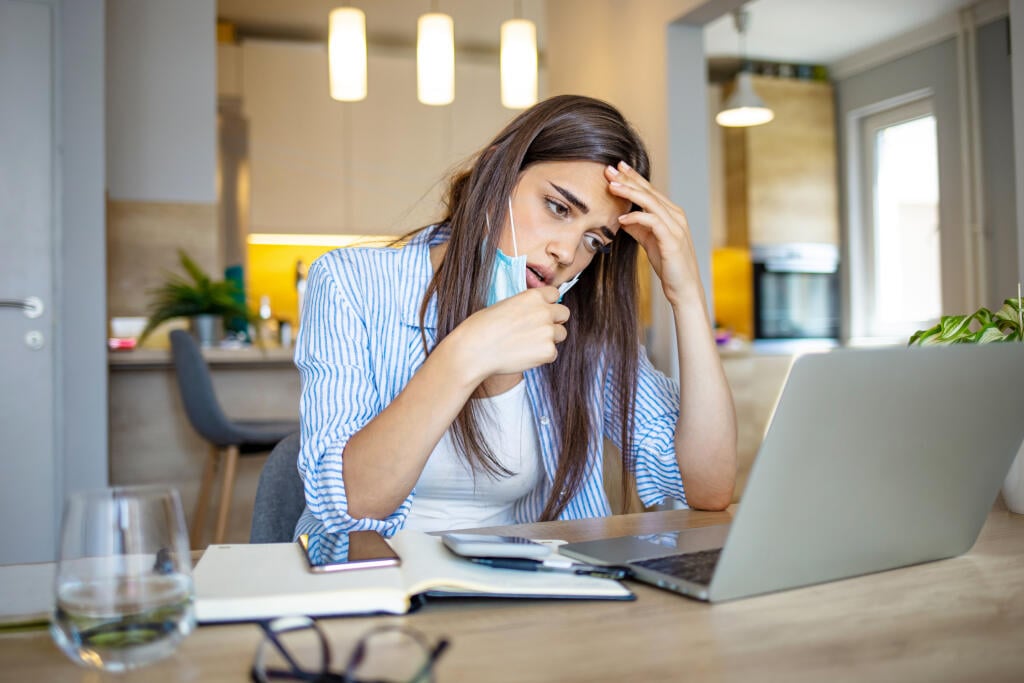 Business woman in mask sitting at desk feels unhealthy put hand where is lungs, suffering from repeated coughing and breath difficulties. Risk coronavirus 2019-ncov contamination