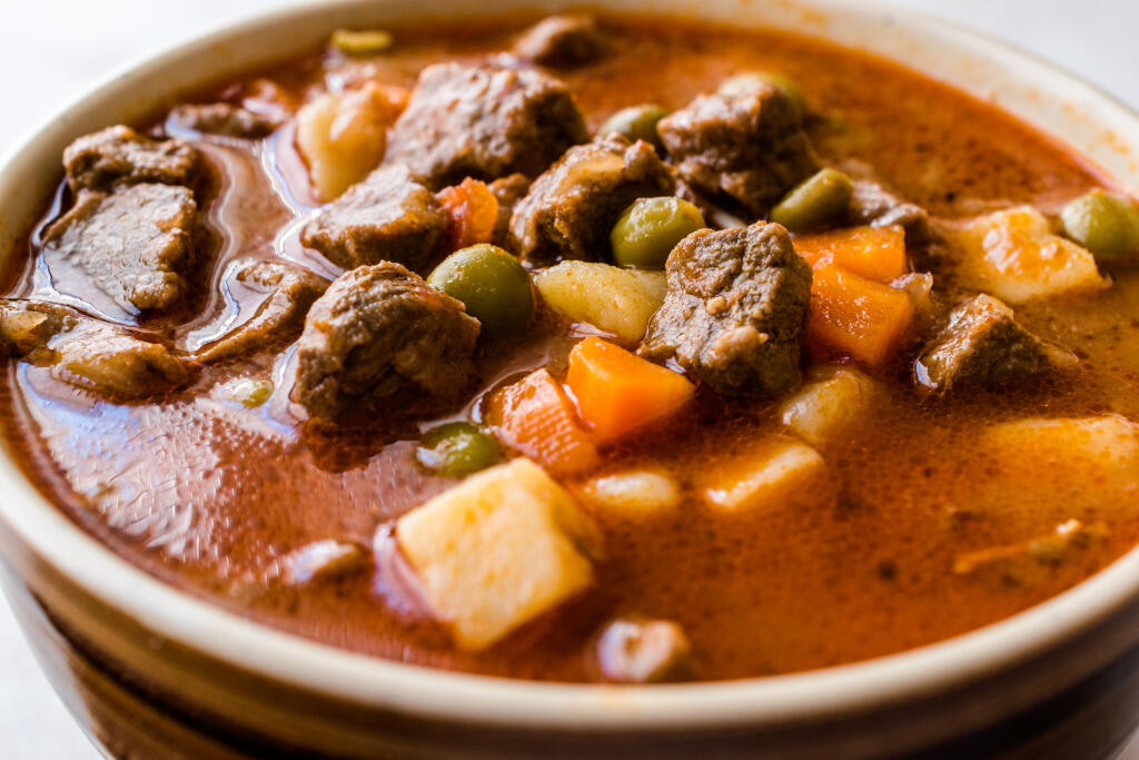 Tasty Hungarian Hot Goulash Soup Bograch or Gulas Lamb Meat Stew with Whole Grain Bread on Wooden Surface at Restaurant. Traditional Food.