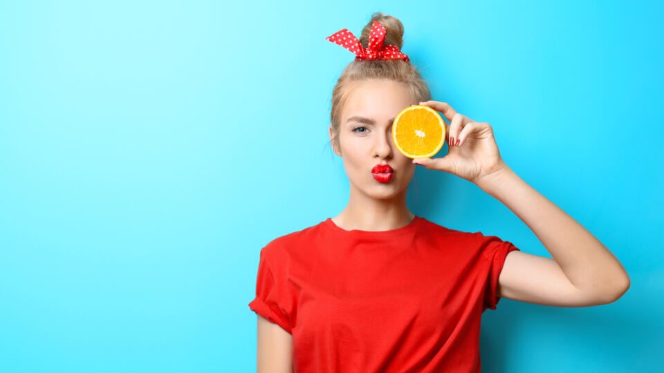 Young,Beautiful,Woman,With,Orange,On,Blue,Background