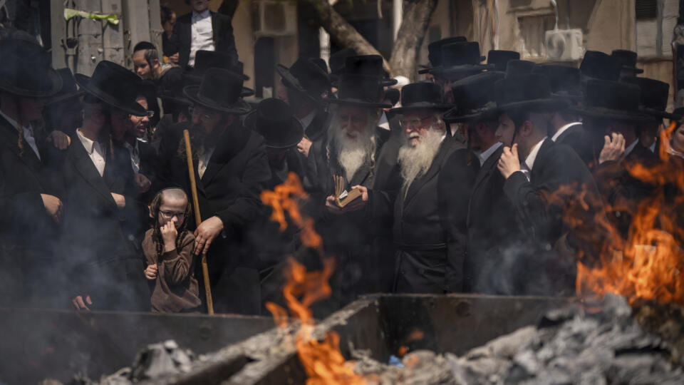 Ultraortodoxní židovskí muži stoja pri kontajneri, v ktorom spaľujú kvasené pokrmy v rámci záverečných príprav na sviatok nekvasených chlebov - pesach v Jeruzaleme v pondelok 22. apríla 2024.