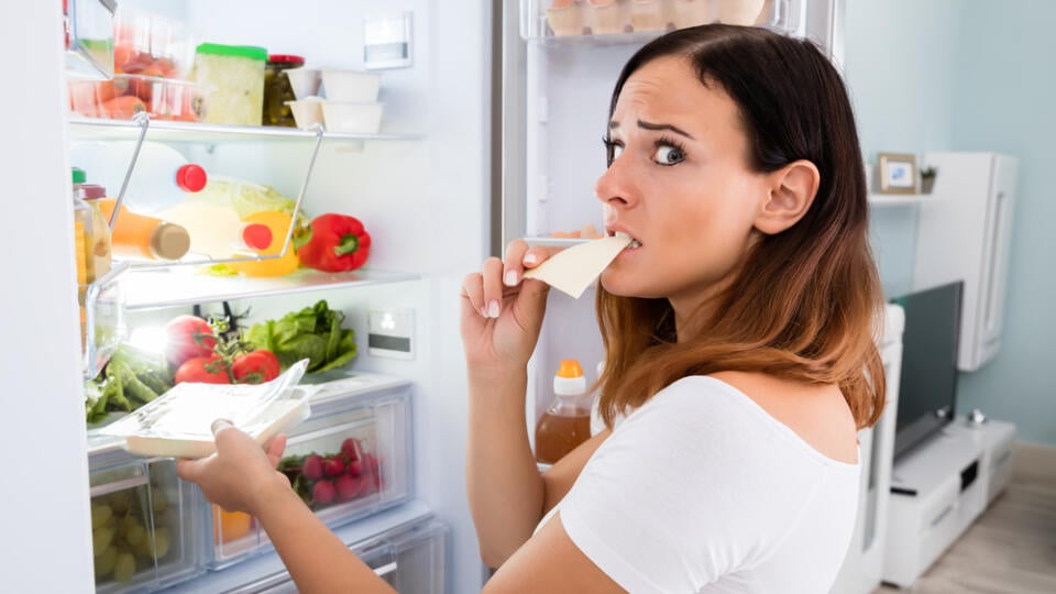 Young,Woman,Eating,Slice,Of,Cheese,In,Front,Of,Open