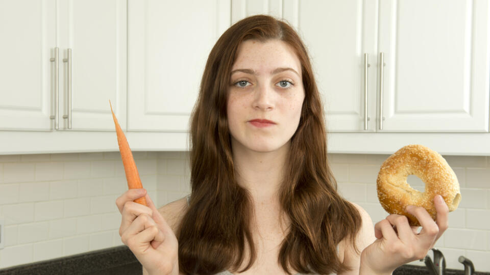 Young,Woman,Holds,A,Carrot,And,A,Bagel,In,A