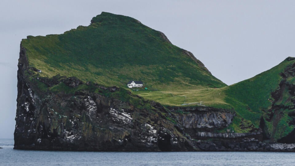 Lonely house on Ellidaey island in Vestmannaeyjar archipelago, Iceland. Rocky and green island. Nordic landscape.