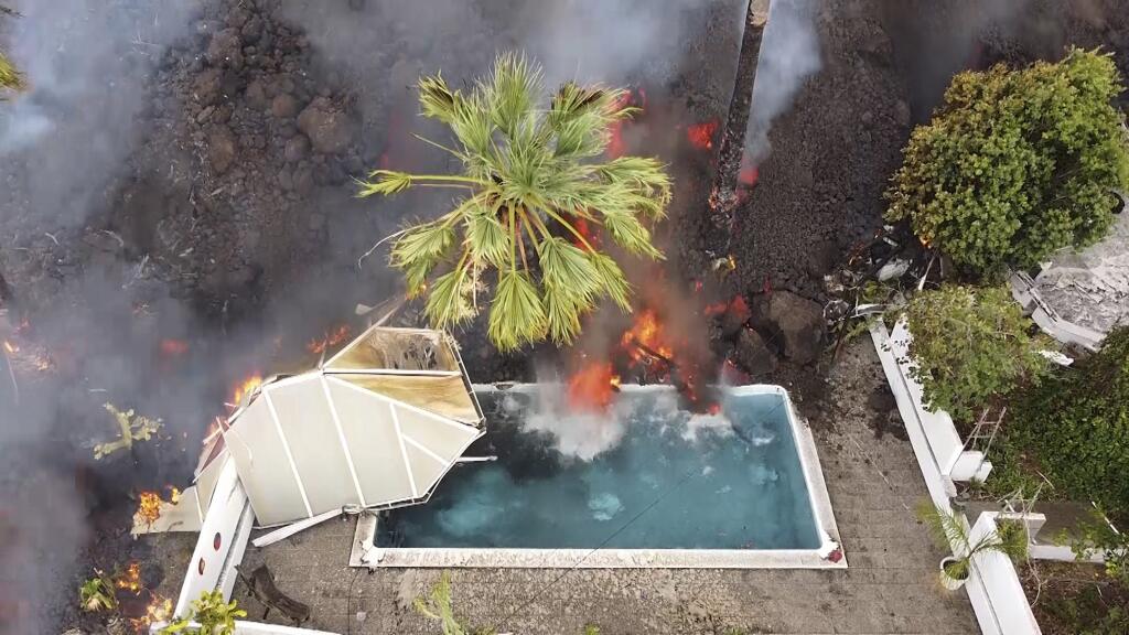 WA 19 La Palma - Hot lava hits the pool after the eruption of La Cumbre Vieja volcano on the Spanish island of La Palma, which is part of the Canary Islands early Monday morning, September 20, 2021. PHOTO TASR / AP Hot lava reaches a swimming pool after an eruption of a volcano on the island of La Palma in the Canary Islands, Spain, Monday, Sept.  20, 2021. Giant lava rivers tumble slowly but steadily into the sea after a volcano erupts on a Spanish island in northwestern Africa.  Th