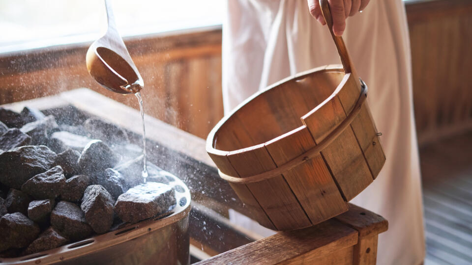 Man,Pouring,Water,Onto,Hot,Stone,In,Sauna,Room.,Steam