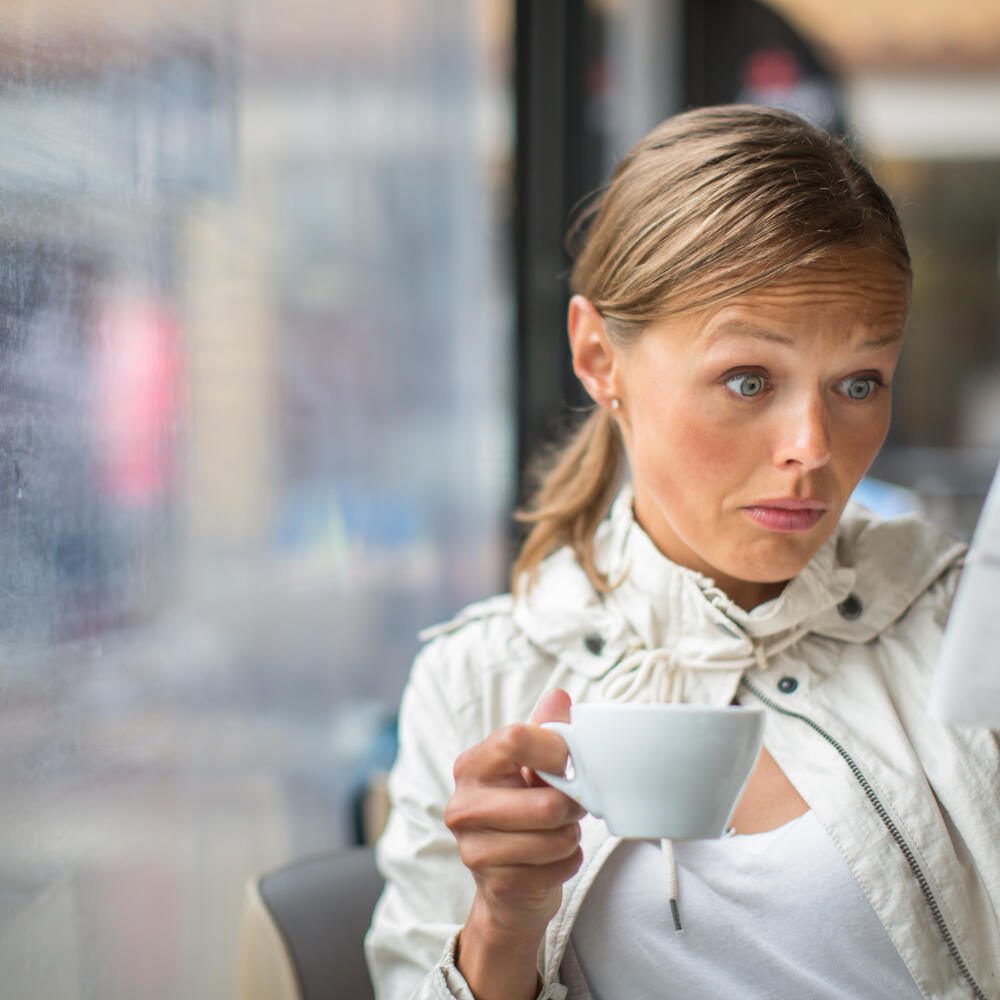Pretty, young woman baffled with the bill in a coffeeshop/restaurant