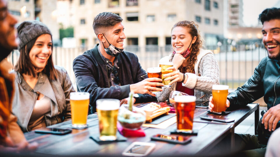 Young,Friends,Drinking,Beer,With,Open,Face,Mask,-,New