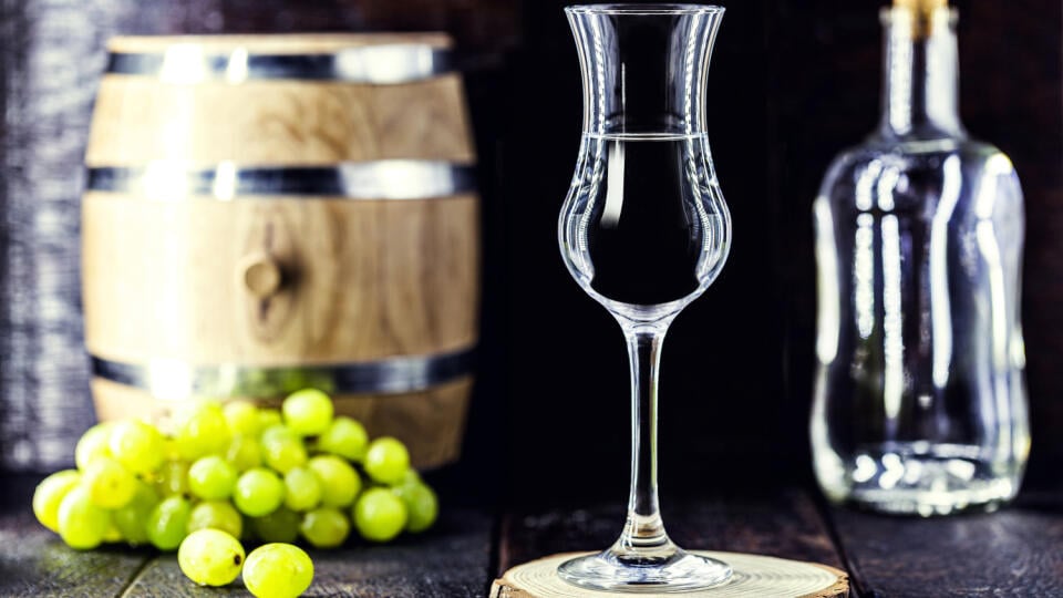 Glass of brandy based on grapes, called bagaceira in Portugal and in Italy Grappa or Graspa, with oak barrel in the background
