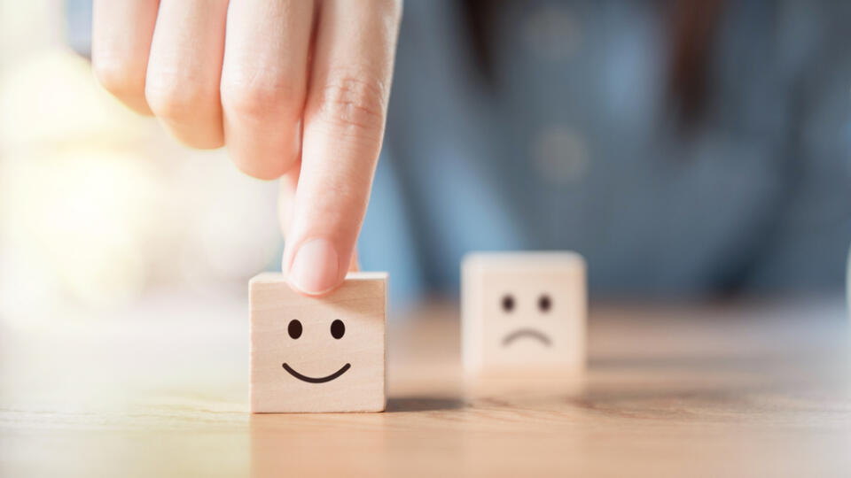 Close,Up,Customer,Hand,Choose,Smiley,Face,And,Blurred,Sad