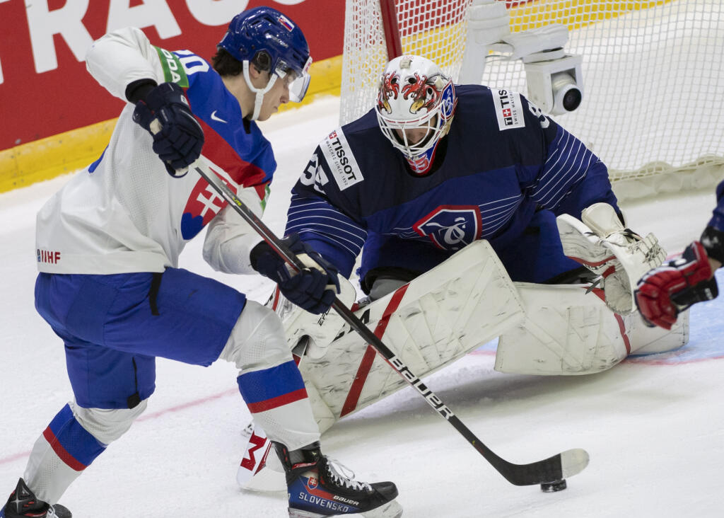Na snímke slovenský hokejista Juraj Slafkovský (vľavo) a brankára Francúzska Corentin-Henri Buysse v úvodnom zápase slovenskej hokejovej reprezentácie v základnej A - skupine Francúzsko - Slovensko na 85. majstrovstvách sveta v ľadovom hokeji v Helsinkách v piatok 13. mája 2022.