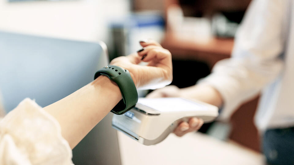 Business female using her smart watch, paying a cost, over the paying device.