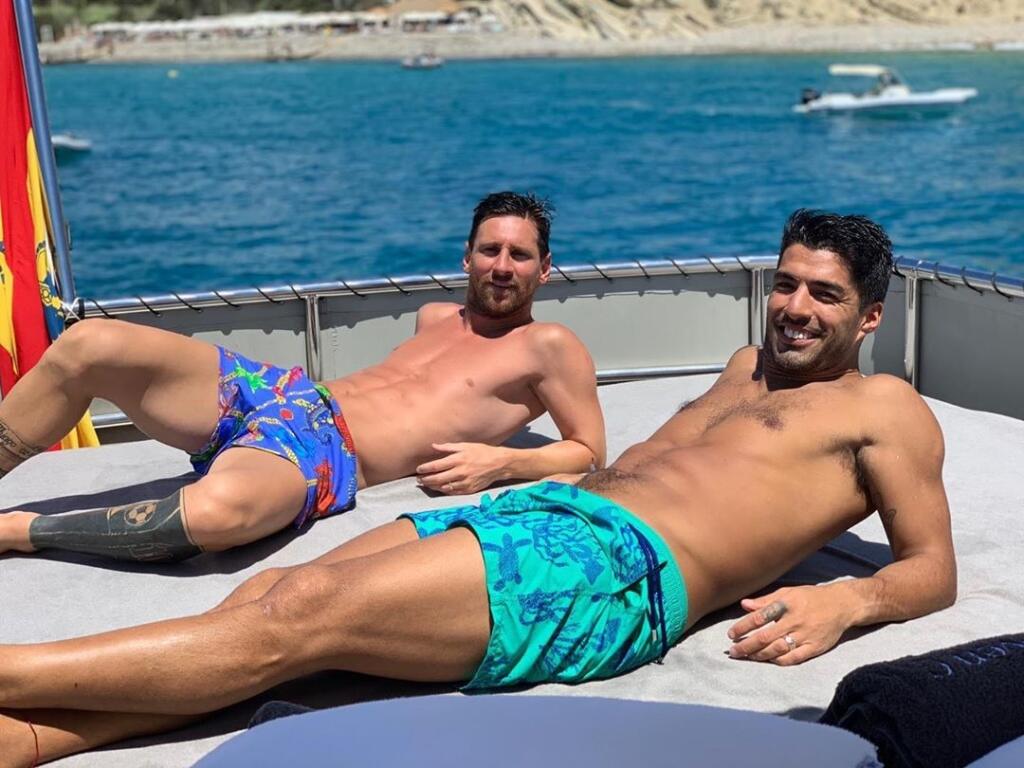 Lionel Messi a Luis Suarez spolu bojujú na trávniku a aj oddychujú.