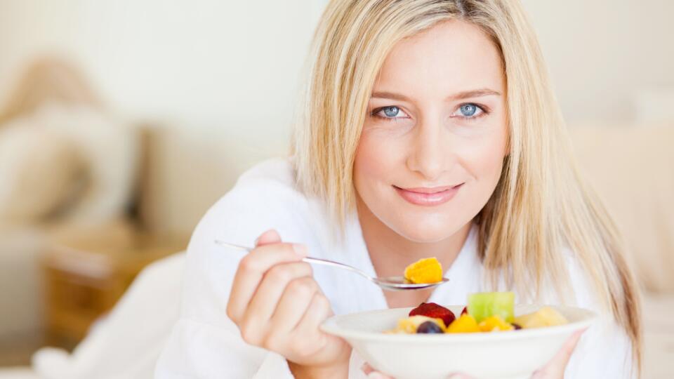 young woman eating breakfast in bed