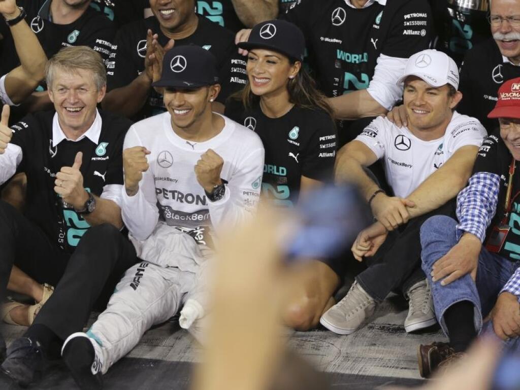 Mercedes driver Lewis Hamilton of Britain celebrates with his partner American singer Nicole Scherzinger and his teammate Mercedes driver Nico Rosberg of Germany in the Mercedes pits after winning the Emirates Formula One Grand Prix to clinch the Formula One world championship at the Yas Marina racetrack in Abu Dhabi, United Arab Emirates, Sunday, Nov. 23, 2014. (AP Photo/Kamran Jebreili)