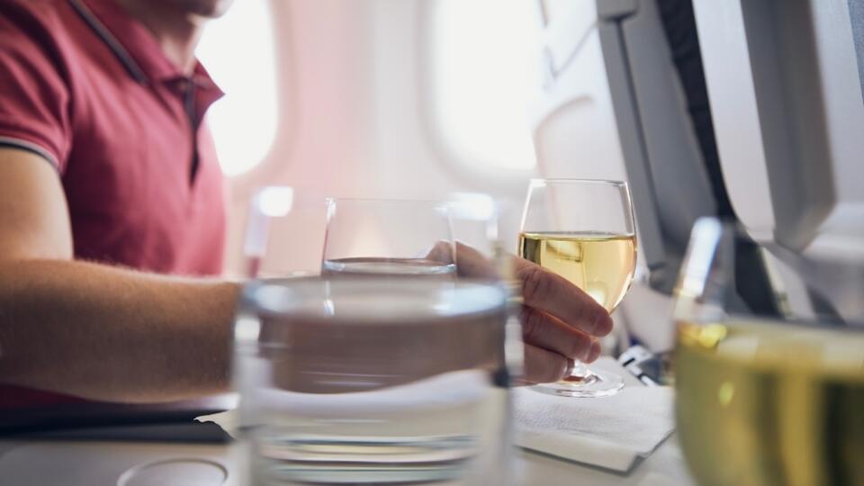 Man,Enjoying,Drink,During,Flight.,Passenger,Holding,Glass,Of,White