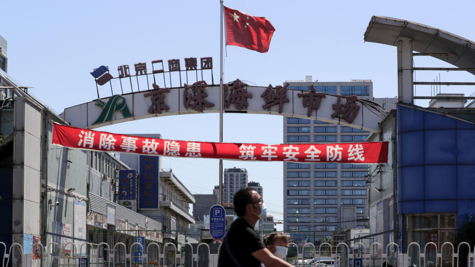 JB 40 Peking - Muž a dieťa s ochrannými rúškami na tvári na zabránenie šíreniu nového koronavírusu prechádzajú na elektrickej kolobežke okolo veľkoobchodného trhu s rybami a inými morskými živočíchmi, ktorý je zavretý pre inšpekciu v čínskom Pekingu 14. júna 2020. Čína oznámila v nedeľu 57 nových prípadov nákazy koronavírusom, čo je najviac za jeden deň od apríla. Údaje prišli v čase, keď rastú obavy z opätovného rozšírenia koronavírusovej choroby. Nové ohnisko nákazy však bolo teraz spojené s t