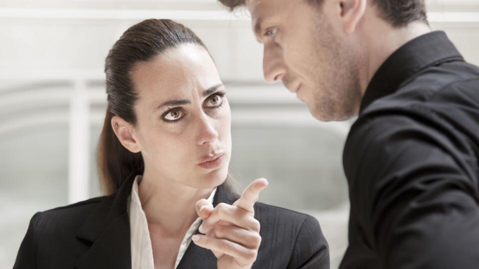 Business people in office conflict. Furious threatening woman bullying and scolding a harassed male coleague. Couple expressing anger and displeasure