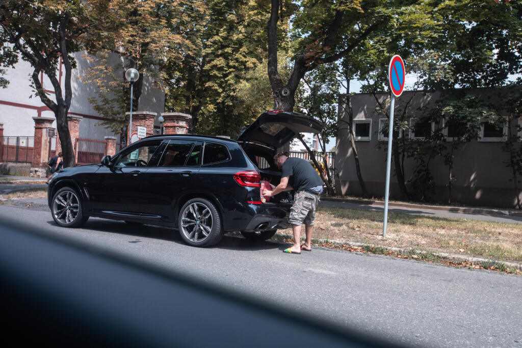 Spevák nakladá Denisinu batožinu do auta.
