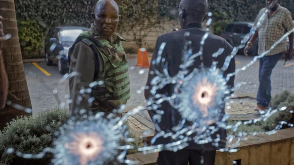 A member of the security forces is seen reflected in a window as he looks at bullet-holes, at a hotel complex in Nairobi, Kenya Tuesday, Jan. 15, 2019. Terrorists attacked an upscale hotel complex in Kenya's capital Tuesday, sending people fleeing in panic as explosions and heavy gunfire reverberated through the neighborhood. (AP Photo/Ben Curtis)