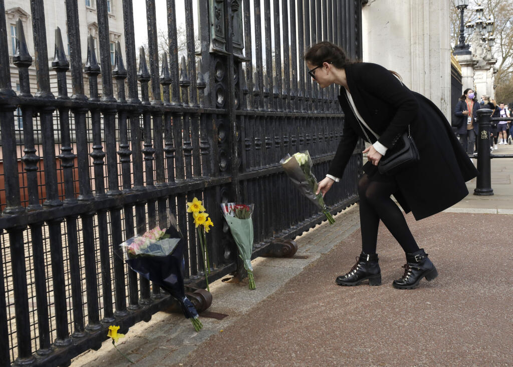 Žena kladie kvety pred bránu Buckinghamského paláca po prečítaní oznámenia o úmrtí britského princa Philipa 9. apríla 2021 v Londýne.
