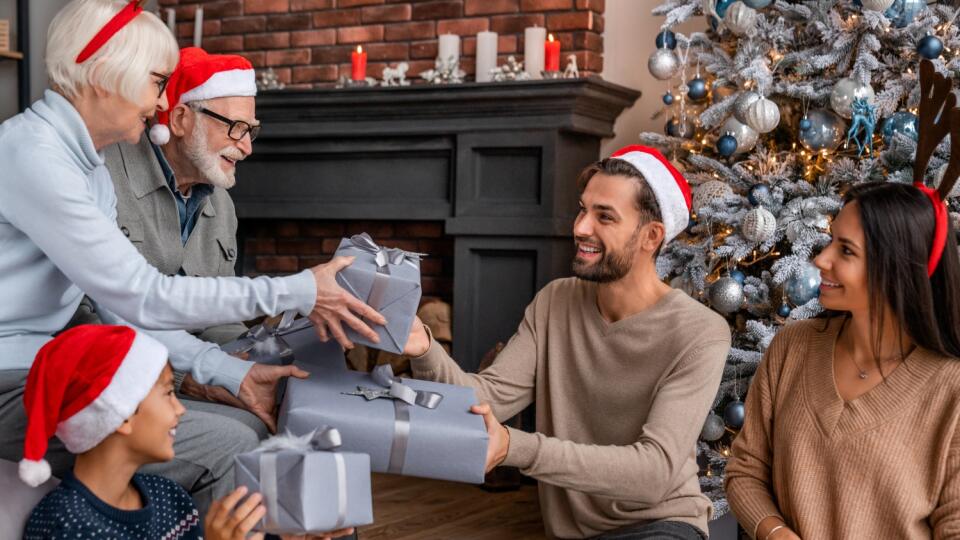 Happy,Family,Sitting,Near,Christmas,Tree,In,Living,Room,Exchanging