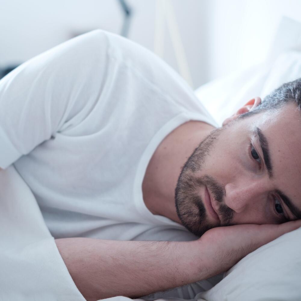 Depressed man lying in his bed and feeling bad