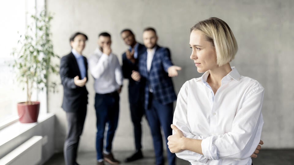 Sexism And Bullying At Work. Unhappy Victimized Business Lady Standing While Her Male Coworkers Whispering Behind Her Back In Modern Office. Workplace Discrimination Problem, Female Rights. Free Space