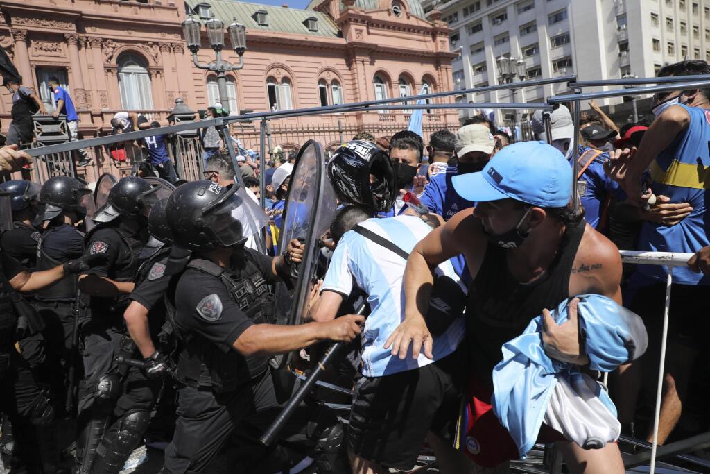 KK6 Buenos Aires - Policajti v potýčke s fanúšikmi počas rozlúčky s argentínskym futbalistom Diegom Maradonom pred prezidentským palácom 26. novembra 2020 v Buenos Aires. Telo futbalistu Diega Maradonu vo štvrtok vystavili v sídle argentínskej federálnej vlády. O osobnú rozlúčku prejavili záujem davy ľudí. Neskôr sa však situácia vyhrotila, fanúšikovia sa v snahe dostať dnu hádzali na policajtov fľašky či kusy oplotenia. Bezpečnostné zložky v jednom prípade použili slzotvorný plyn. FOTO TASR/AP