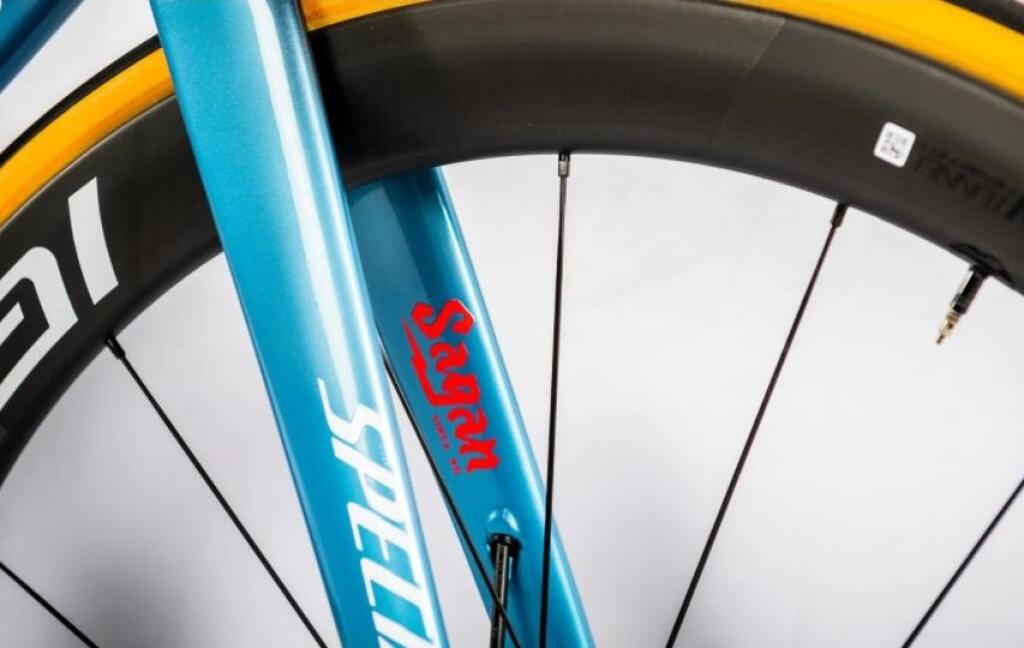 Saganov nový bicykel má bledomodrý rám s malými červenými doplnkami a okrem názvu a loga stajne ho zdobí aj meno Žilinčana s citátom „Nikdy nezlyháš, kým sa neprestaneš snažiť.“