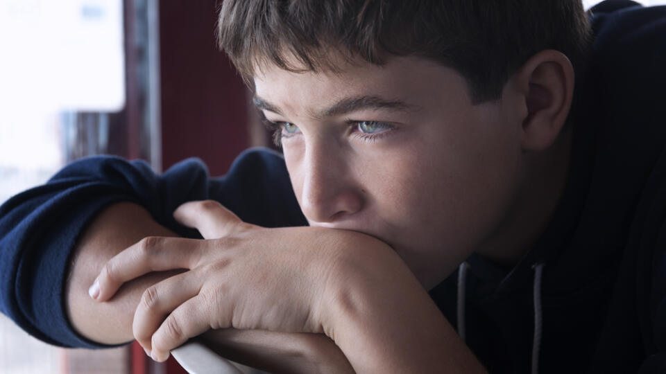 Pensive,Child,Looking,Through,A,Window