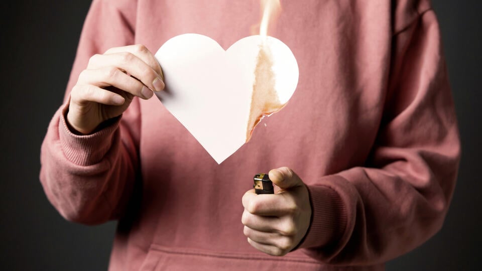 The woman sets the heart on fire, the end of the romantic relationship. Young girl sets fire to a white paper heart, declaring war on inequality in the toxic abusive relationship in which she was. 