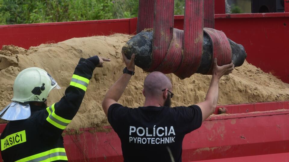 Na snímke policajný pyrotechnik a hasič vykladajú leteckú bombu z čias bombardovania rafinérie Apollo v roku 1944, ktorú našli počas pyrotechnického prieskumu na stavenisku na Chalupkovej ulici v centre Bratislavy pred jej zneškodnením v areáli ministerstva vnútra pri bratislavských Rusovciach v utorok 20. júla 2021. FOTO TASR - Vladimír Benko/MV SR 