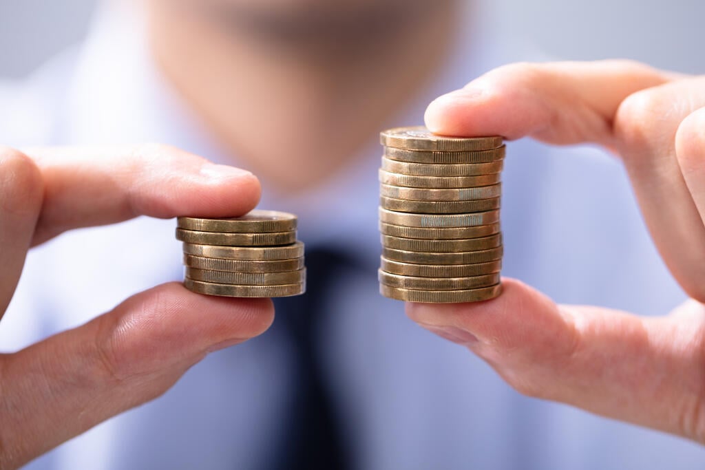 Man,Holding,Two,Coin,Stacks,To,Compare