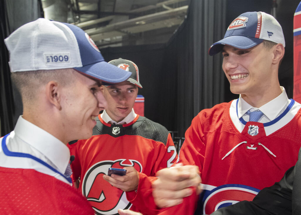 Na snímke slovenskí hokejisti sprava Juraj Slafkovský (Montreal Canadiens), Šimon Nemec (New Jersey Devils) a Filip Mešár (Montreal Canadiens) sa tešia počas prvého kola draftu zámorskej hokejovej NHL v Montreale 7. júla 2022.