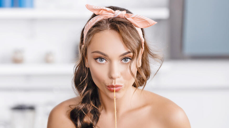 Brunette,Woman,Eating,Spaghetti,And,Looking,At,Camera,Near,Orange