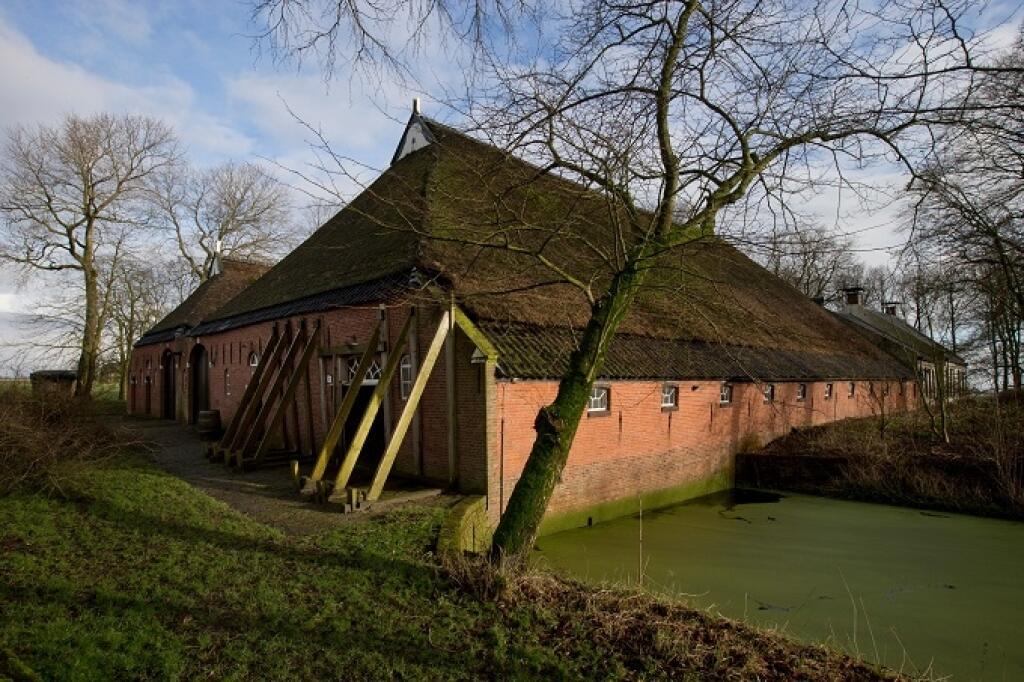 FILE - In this Friday, Jan. 19, 2018 file photo, support beams stabilize an historic farm after a series of small tremors caused by decades of gas extraction, in Hunzinge, in Groningen province, northern Netherlands. The Dutch government has decided to end gas extraction in its northern Groningen region after it proved essential in lowering the risk of damage from small earthquakes. The Dutch cabinet said Thursday, March 29 the maximum yield must be halved by 2022 or earlier, with more cuts late