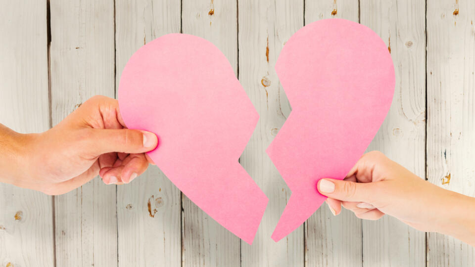 Couple,Holding,Two,Halves,Of,Broken,Heart,Against,Wooden,Background