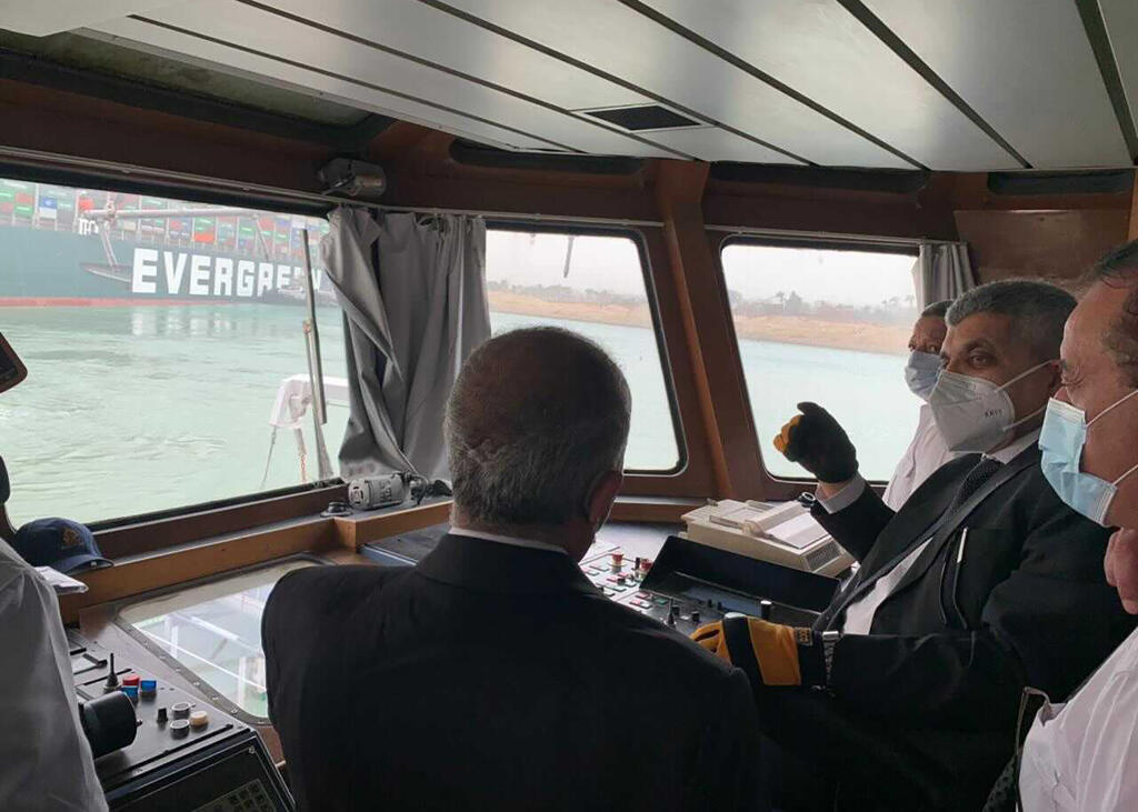 JB 20 Suez - Generál Ossama Rabei, šéf lodnej prepravy v Suezskom prieplave (druhý sprava) hovorí na palube navigačného plavidla s posádkou nákladnej lode Ever Green (v pozadí), ktorá uviazla na plytčine v Suezskom prieplave pri egyptskom meste Suez 24. marca 2021. Jedna kontajnerová loď sa v noci na stredu dostala v Suezskom kanáli na plytčinu a blokuje prieplav, ktorý je dôležitým lodným spojením medzi Áziou a Európu. Cez kanál tiež smeruje veľká časť transportu energií z Blízkeho východu do E