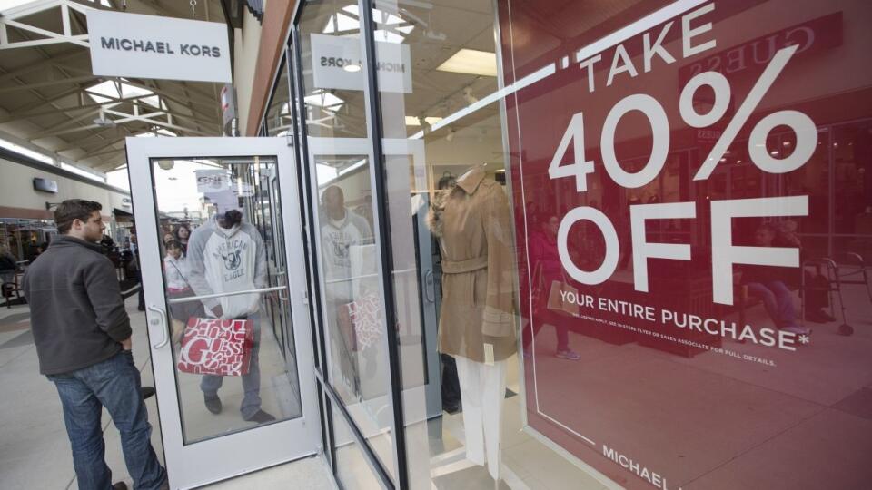 A doorman holds the door for a shopper at a Michael Kors store at the Cincinnati Premium Outlets, Friday, Nov. 27, 2015, in Monroe, Ohio. Early numbers aren’t out yet on how many shoppers headed to stores on Thanksgiving. But it’s expected that more than three times the number of people who shopped on Thanksgiving will venture out to shop on the day after the holiday known as Black Friday. (AP Photo/John Minchillo)