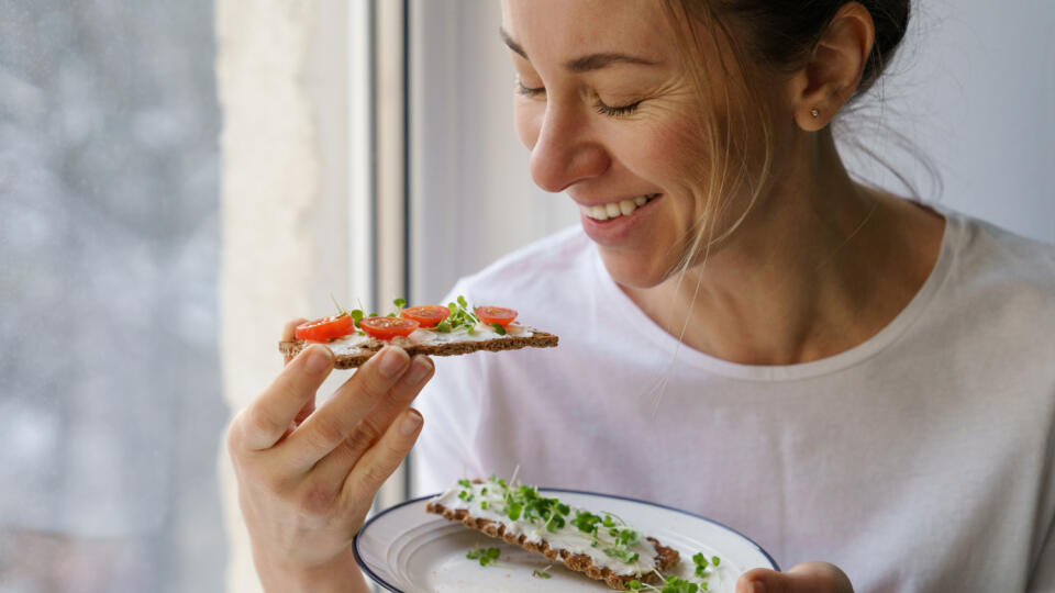 Smiling,Woman,Eating,Rye,Crisp,Bread,With,Creamy,Vegetarian,Cheese