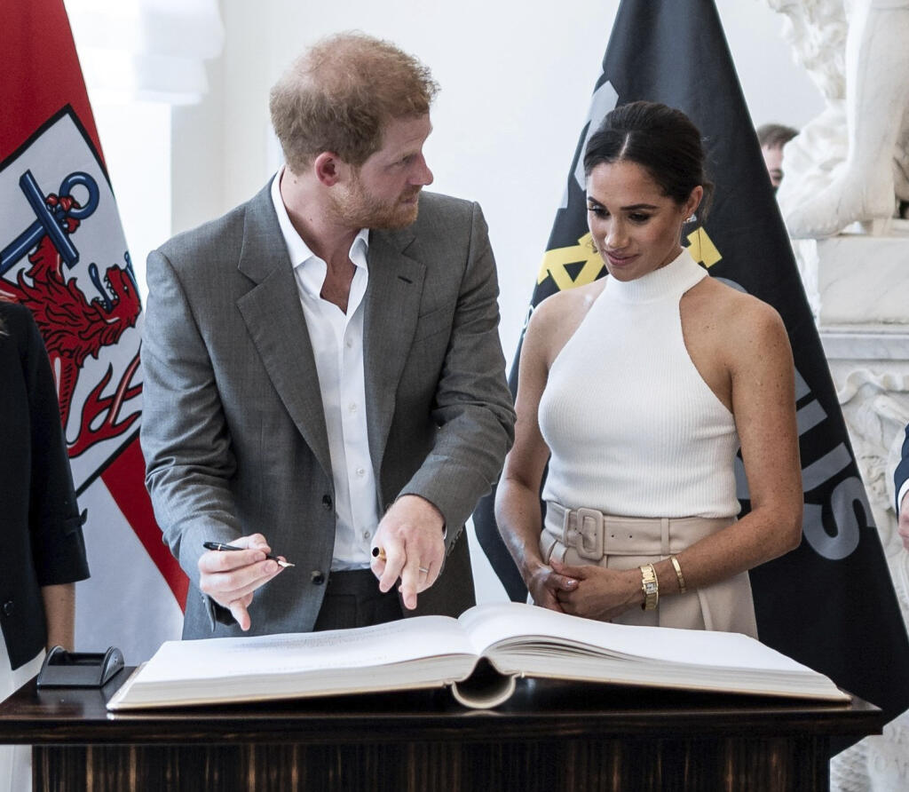 Britský princ Harry a Meghan, vojvodkyňa zo Sussexu, sa zapisujú do knihy hostí počas návštevy v radnici nemeckého mesta Düsseldorf.