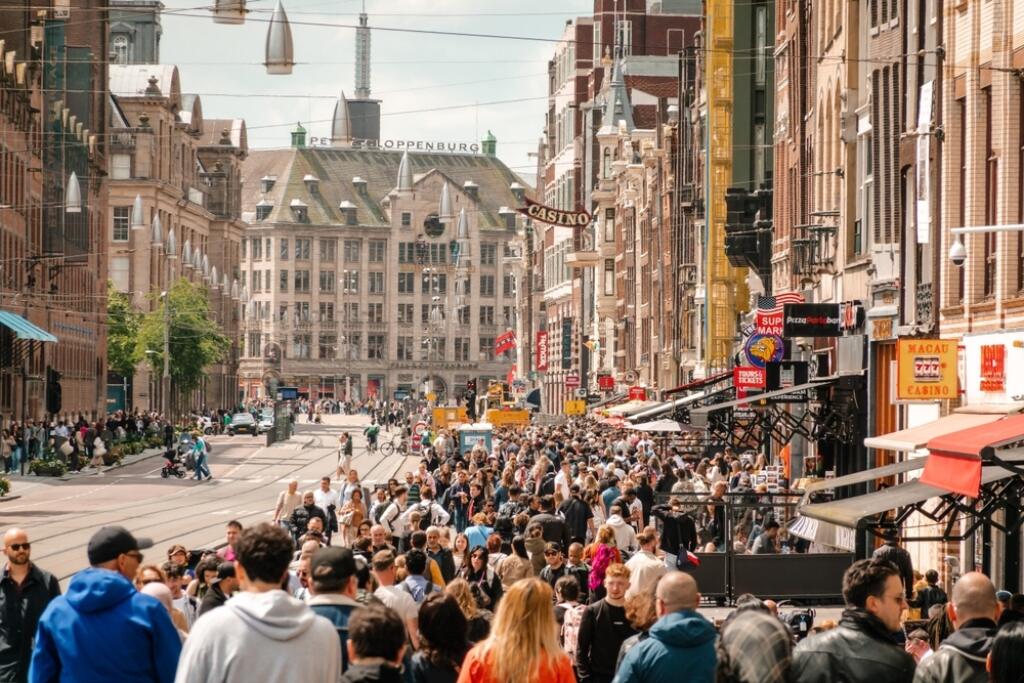 Amsterdam, Netherlands - 09 June 2024: View to touristic street. Crowd of tourists on the foreground, People walking down a typical European street