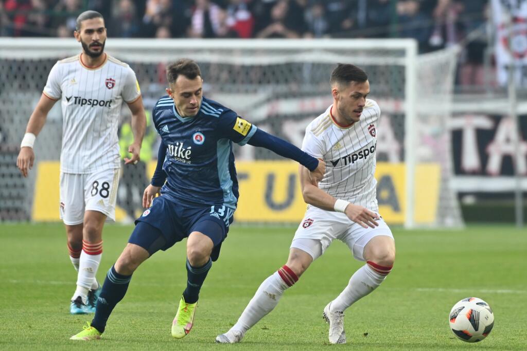 Na snímke zľava hráč Spartaka Kyriakos Savvidis, hráč Slovana Dejan Dražič a hráč hráč Spartaka Martin Bukata v zápase 11. kola futbalovej Fortuna ligy FC Spartak Trnava - ŠK Slovan Bratislava v Trnave v nedeľu 17. októbra 2021. FOTO TASR - Lukáš Grinaj