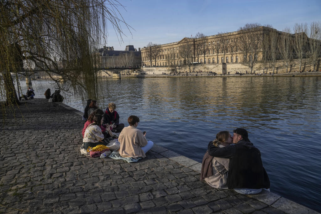 Ľudia sedia na brehu Seiny v Paríži v utorok 21. februára 2023. Francúzsko zaznamenalo rekordných 31 dní po sebe bez výraznejších dažďových zrážok, oznámila v utorok meteorologická služba Meteo France.