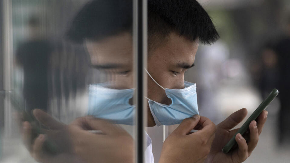 WA 2 Peking - Odraz muža v skle, ktorý sa dotýka rúška a pozerá sa do mobilného telefónu v Pekingu vo štvrtok 11. júna 2020. FOTO TASR/AP
A man is reflected as he adjusts his mask as he looks at this smartphone in Beijing on Thursday, June 11, 2020. (AP Photo/Ng Han Guan)